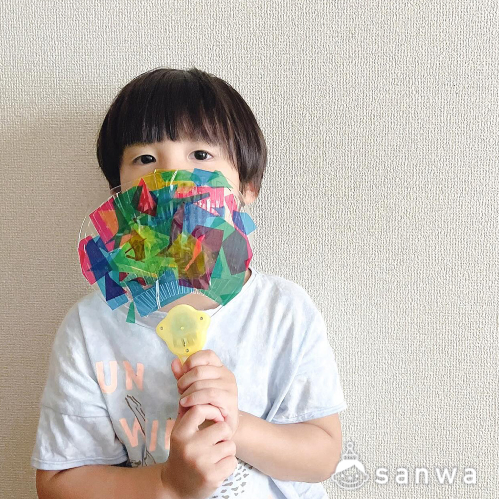 光るうちわを口元で持っている子供